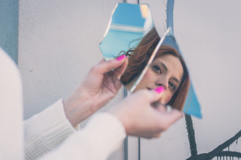 a beautiful young sad woman in the reflection of a broken mirror