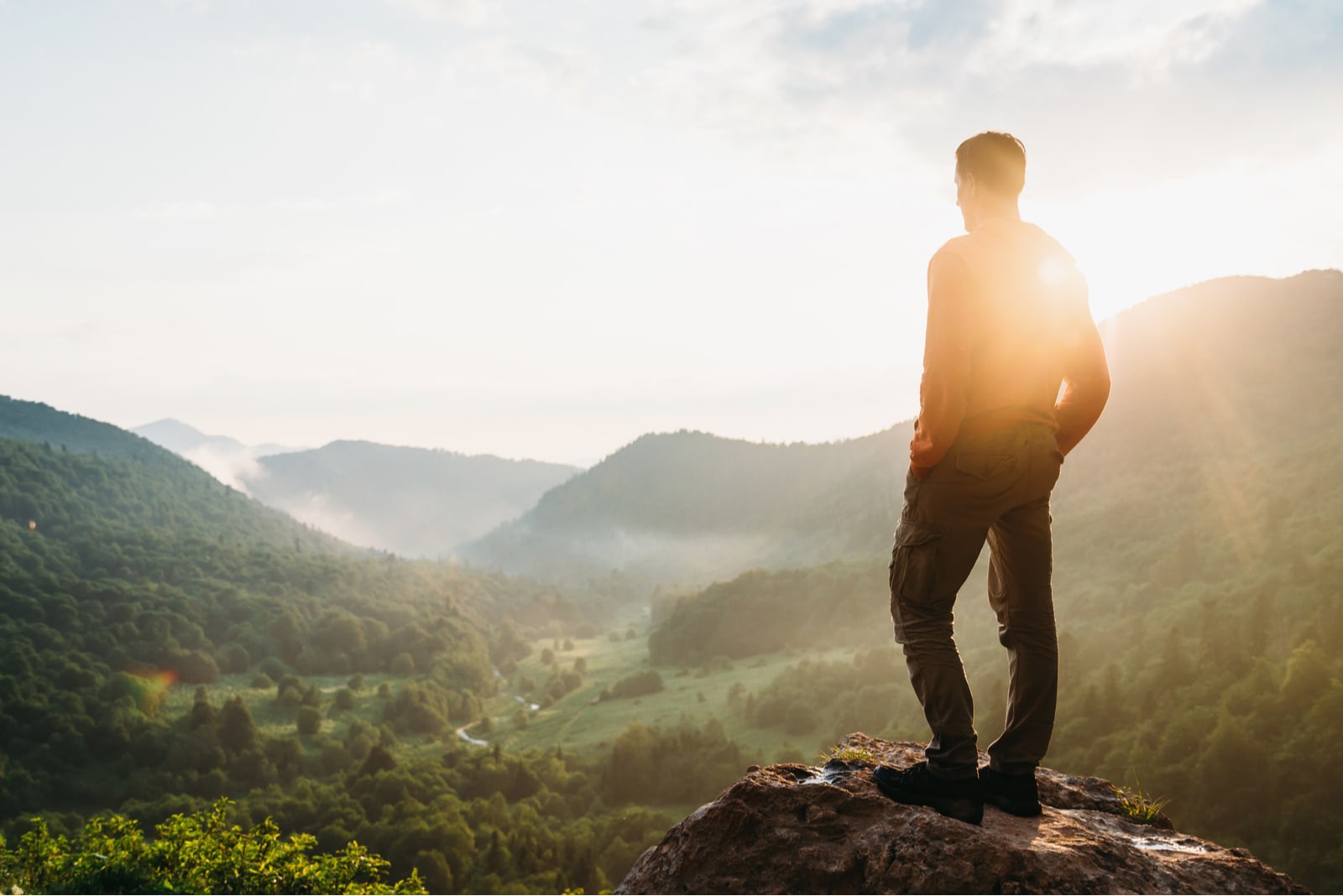 Traveler young man standing in the summer mountains