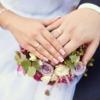 pareja de novios cogidos de la mano con anillos