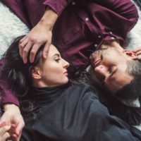 romantic couple lying on cozy carpet and looking at each other