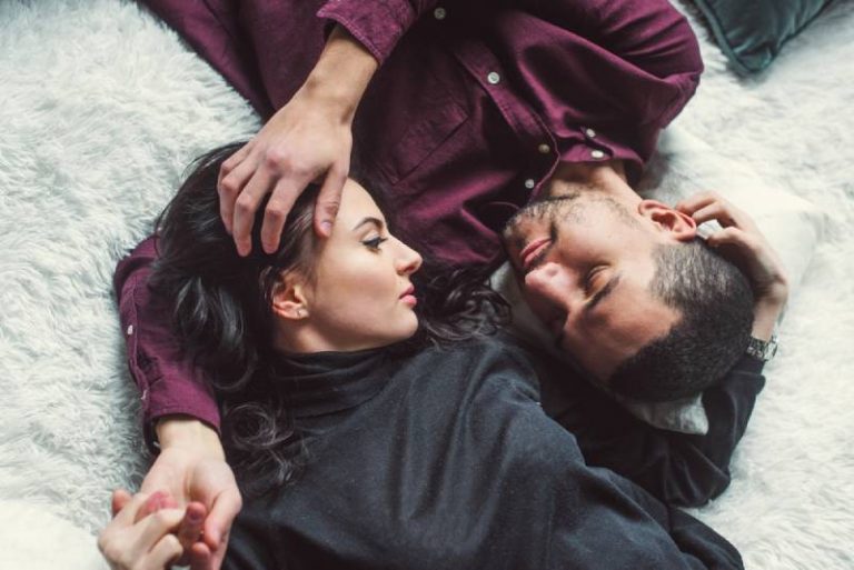 romantic couple lying on cozy carpet and looking at each other