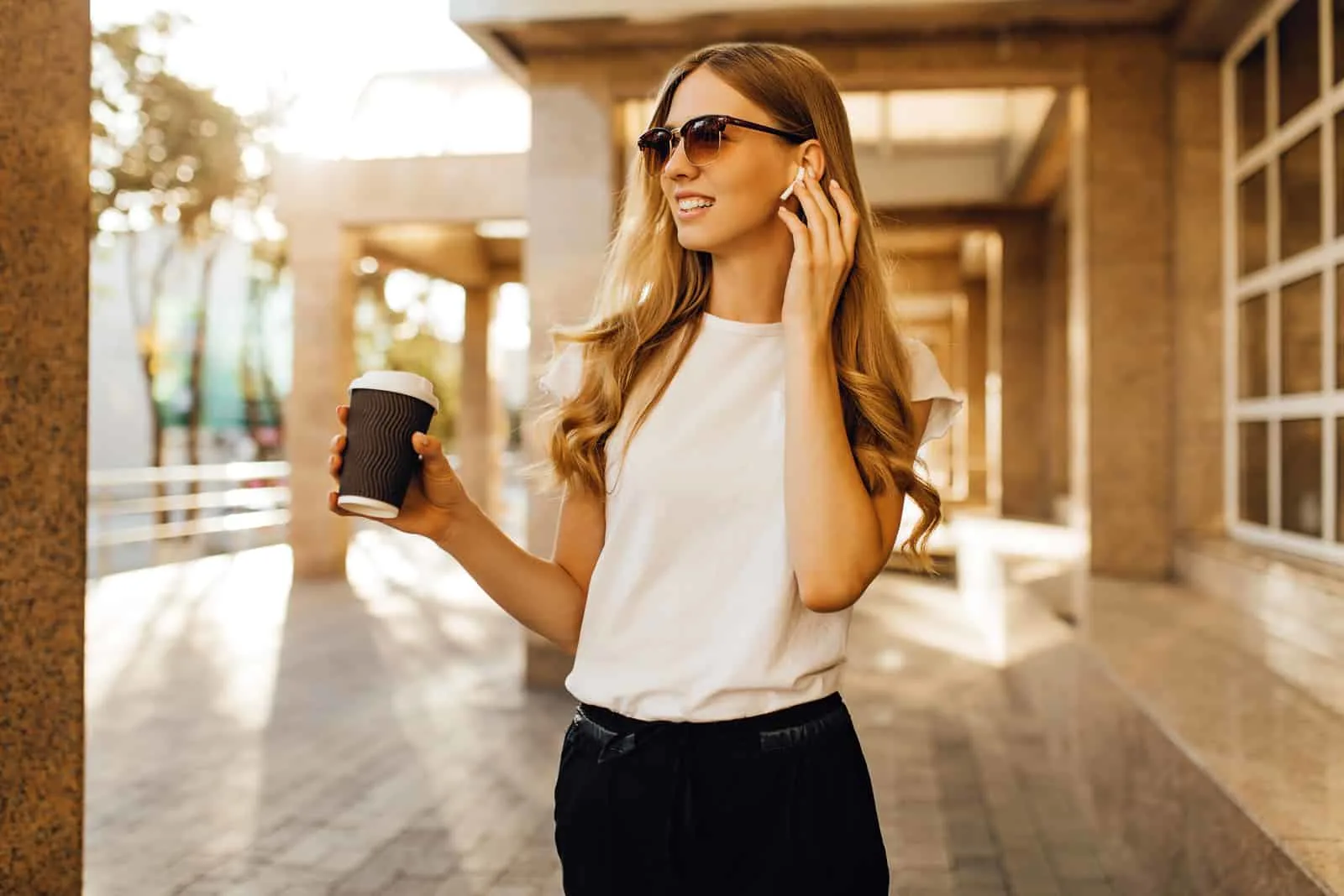 a beautiful young woman with long brown hair stands and holds coffee in her hand