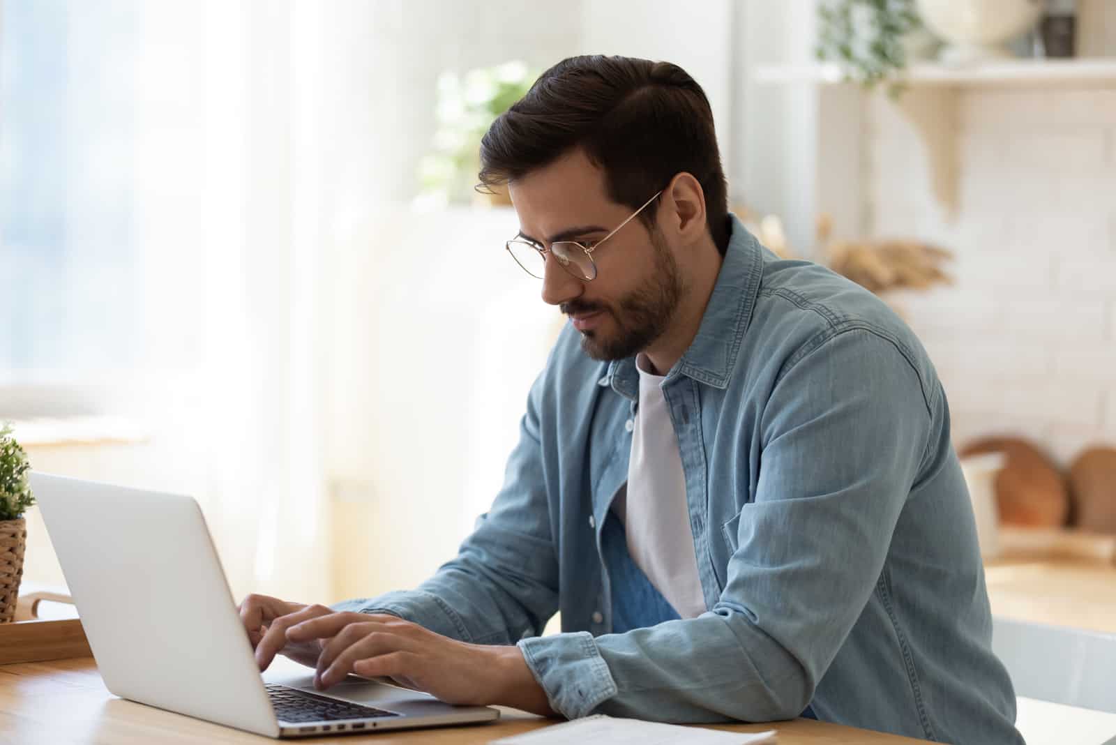 um homem senta-se à frente de um computador portátil e trabalha