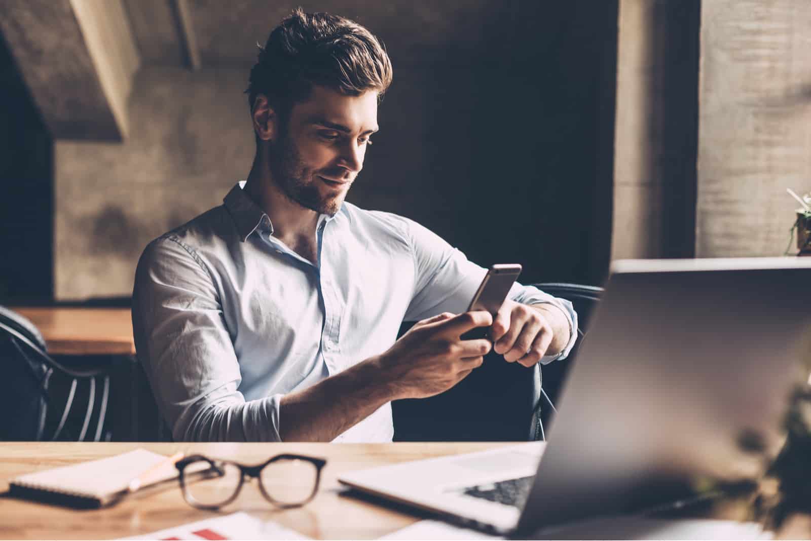 um homem senta-se no escritório e tecla ao telefone