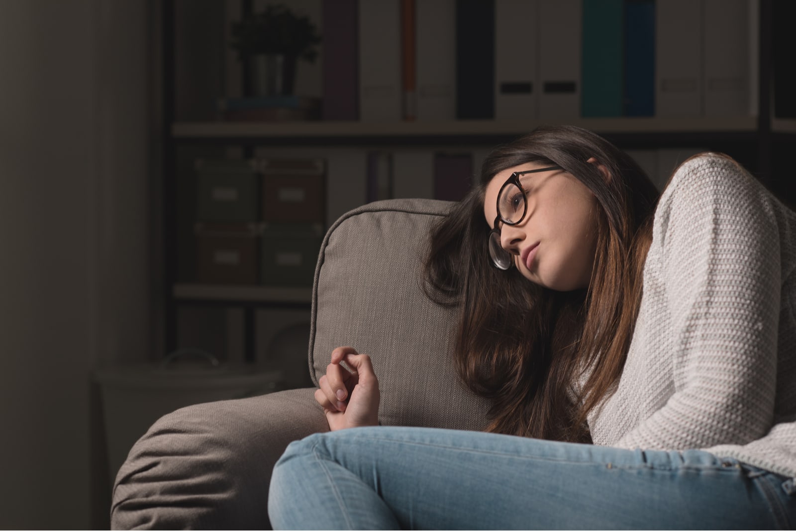 una morena triste con gafas se tumba en el sofá y piensa