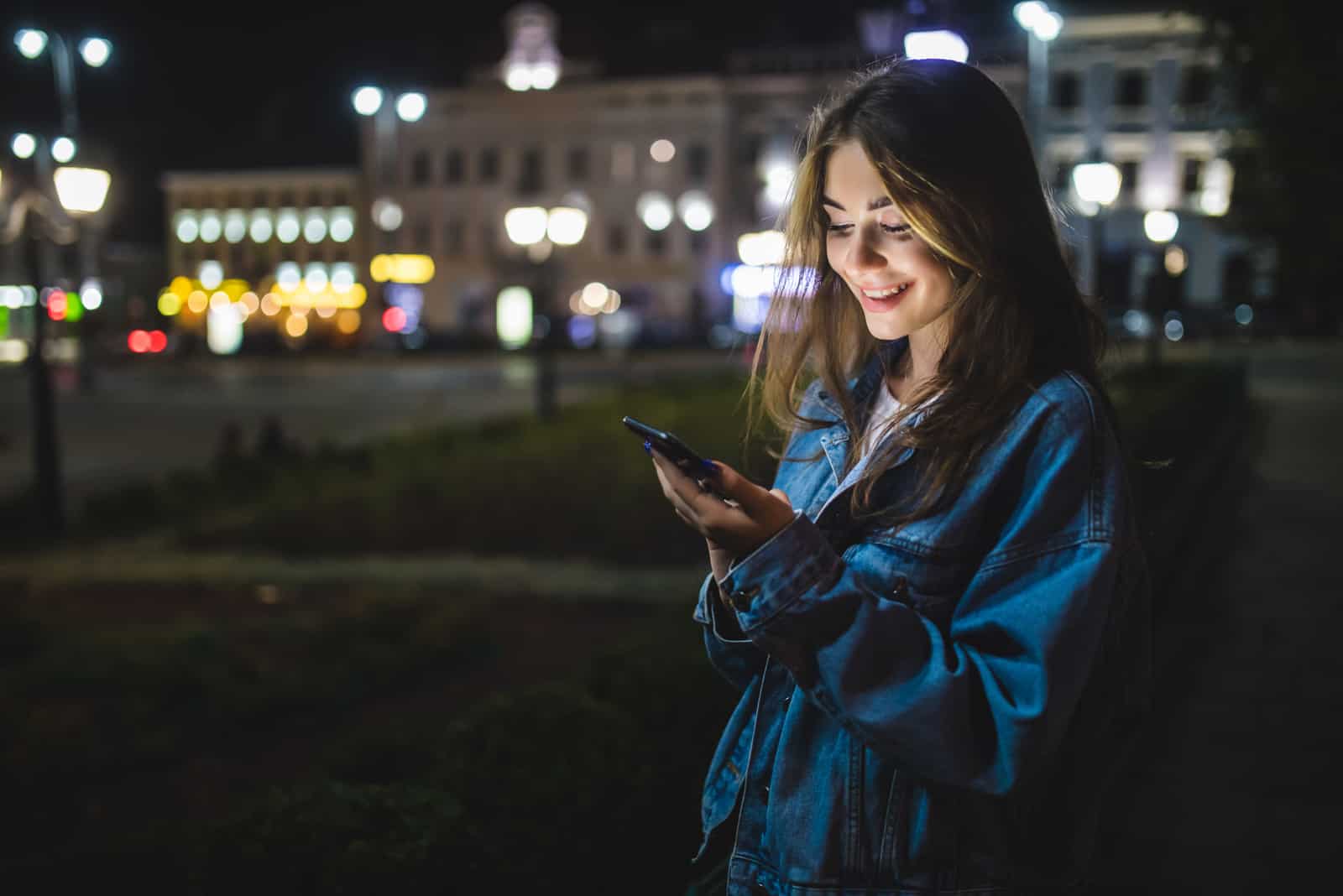 a smiling woman stands and a button on the phone