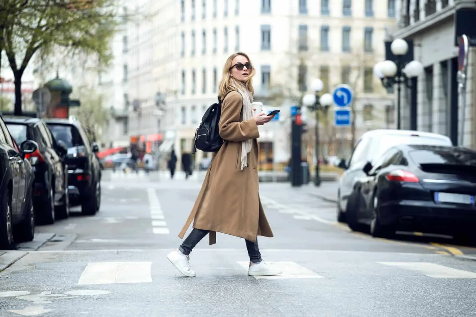 a woman in a brown coat walks down the street