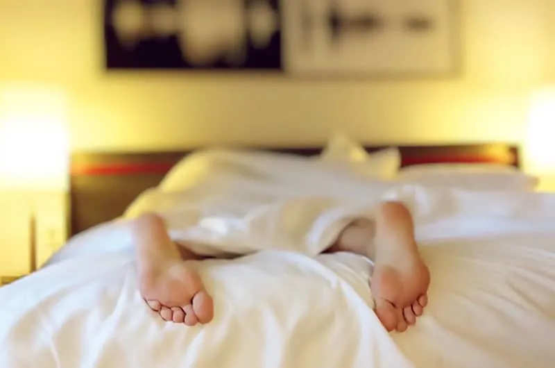 alone sleeping in bed showing 2 feet out of the linen