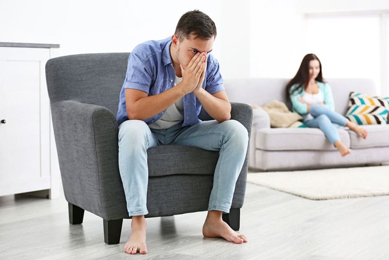 angry man sitting in the living room with his woman