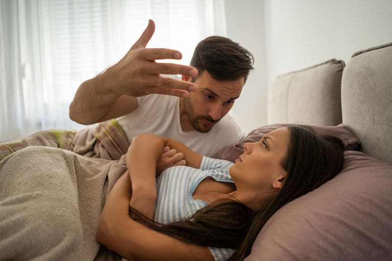 homens zangados a gritar com a namorada na cama