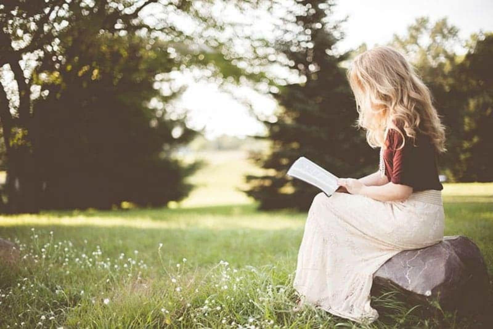 blond woman reading book in nature