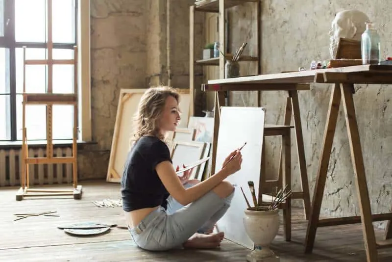 blonde girl sitting and painting on table