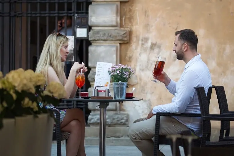 woman and man sitting at cafe table and drinking