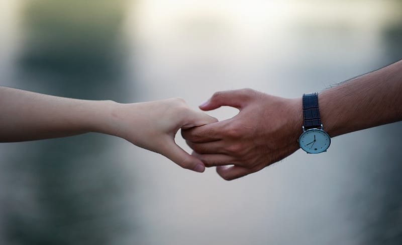couple holding hands with a watch on mans hand