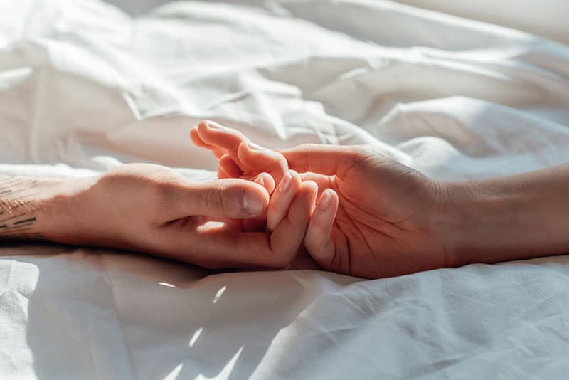 couple holding hands on the bed