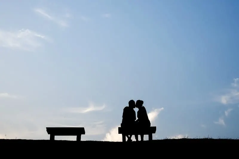 Silhouette of couple kissing on a bench