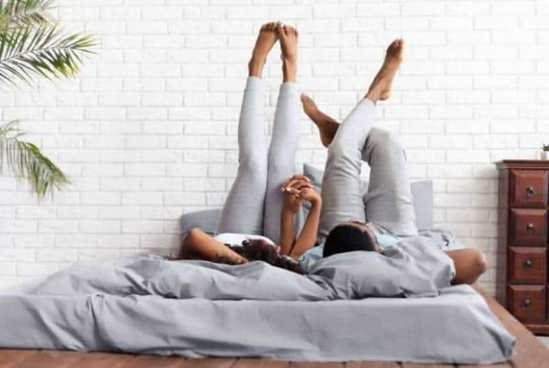 coppia sdraiata sul letto con le gambe alzate