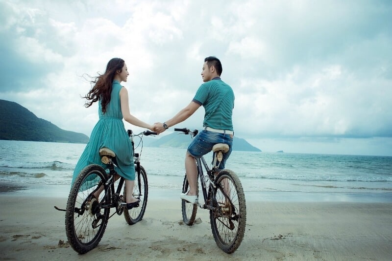 Woman and man sitting on bicycles holding hands