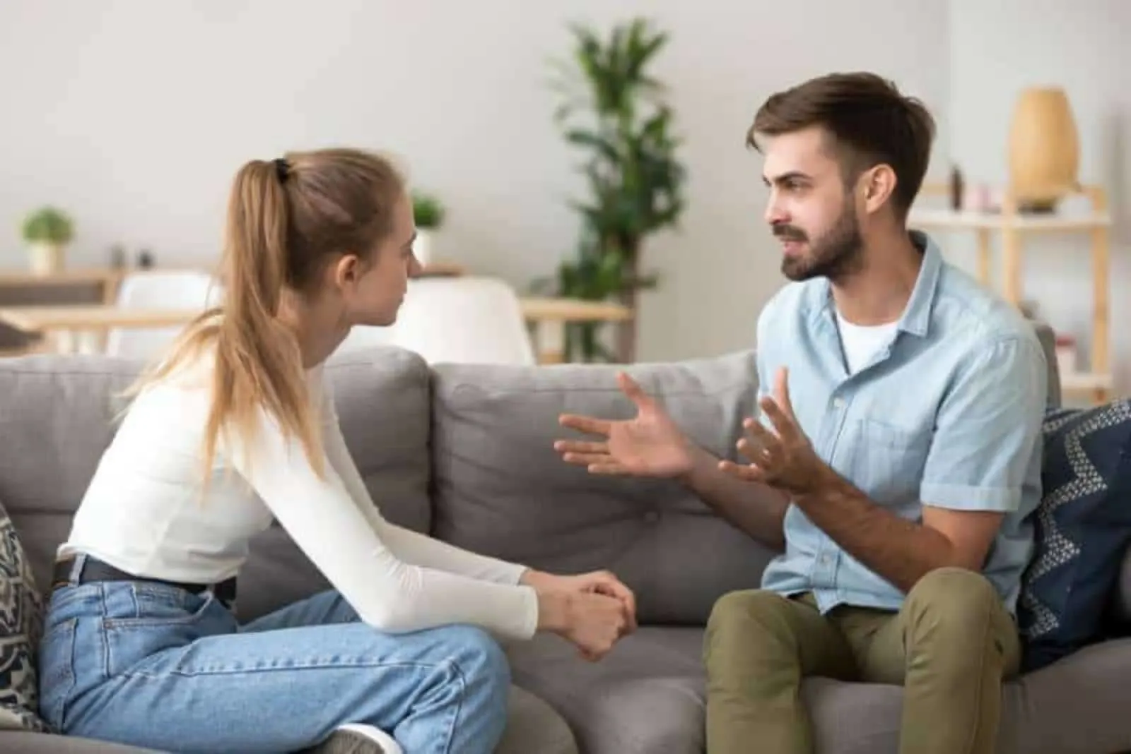 couple serious talking while sitting on sofa