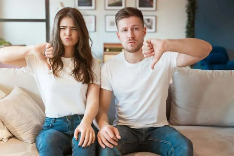 couple sitting at home and gestiruing dislike sign