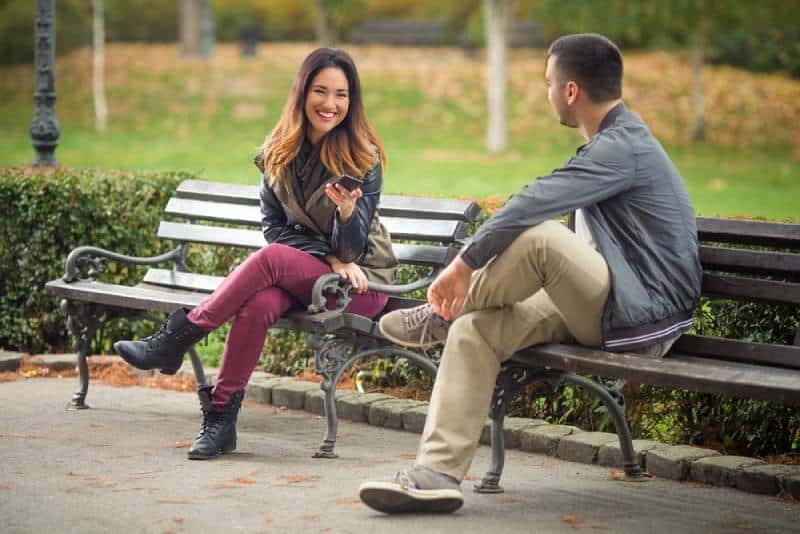 pareja sentada en un banco de un parque y hablando
