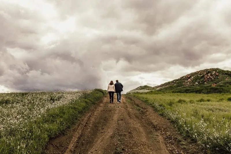 couple walking between green fields
