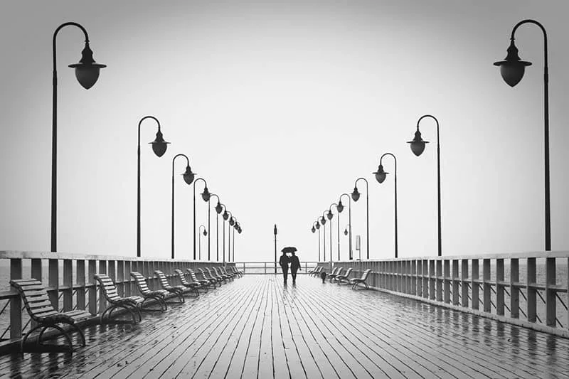 couple walking on boardwalk in black and white