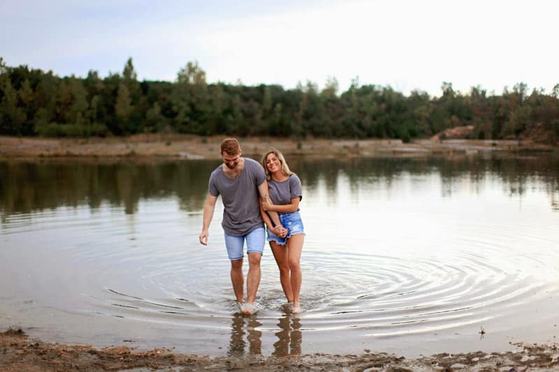 Couple laughing while walking on shallow water