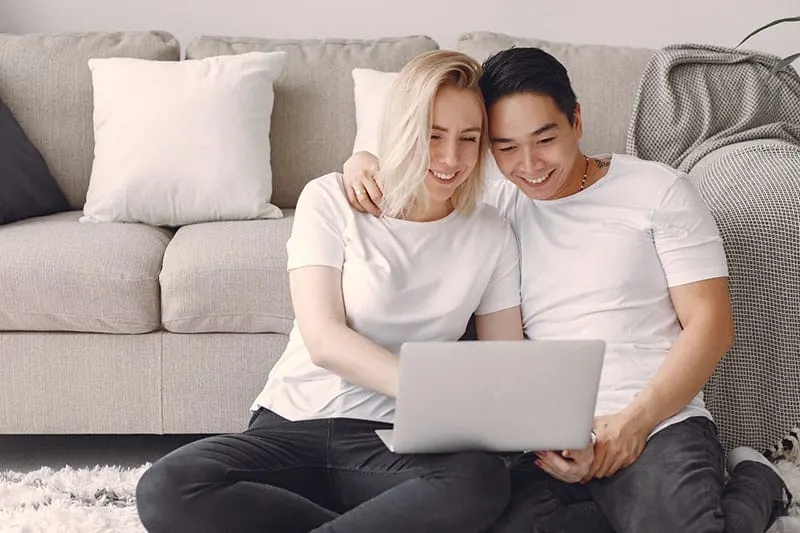 couple in white t shirt watching movie on laptop on the floor