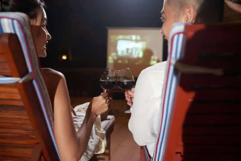 couple watching movie outdoors and cheering glass of wine