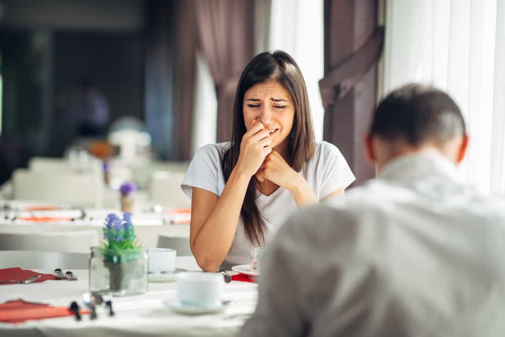 mujer estresada llorando con su novio en la mesa