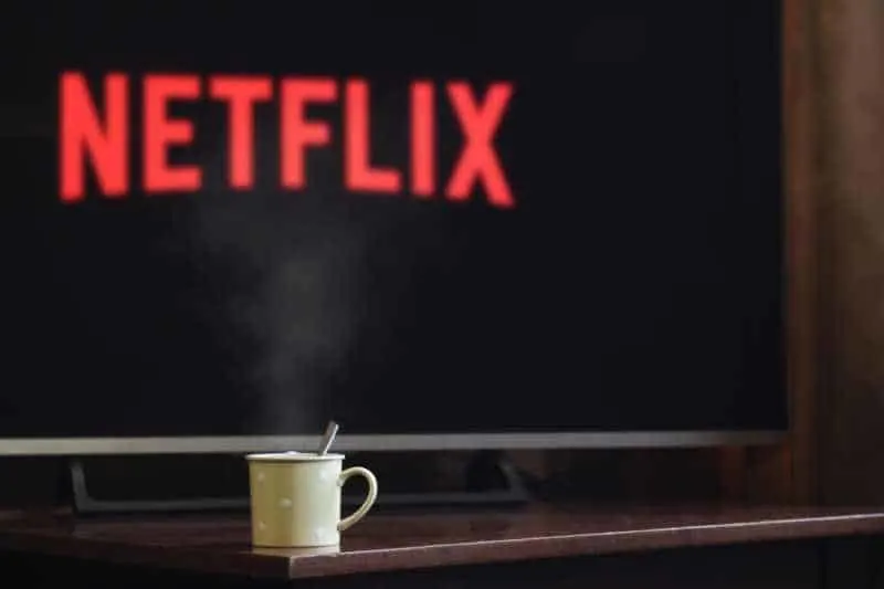 Cup near flat screen television with netflix written on the screen