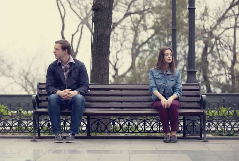 distanced couple sitting on the park bench