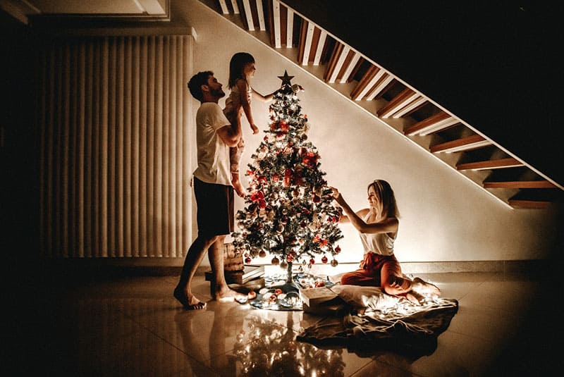 famiglia che decora il proprio albero di Natale sotto le scale