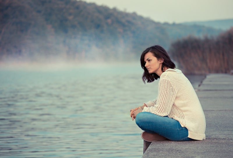 girl sitting by lake