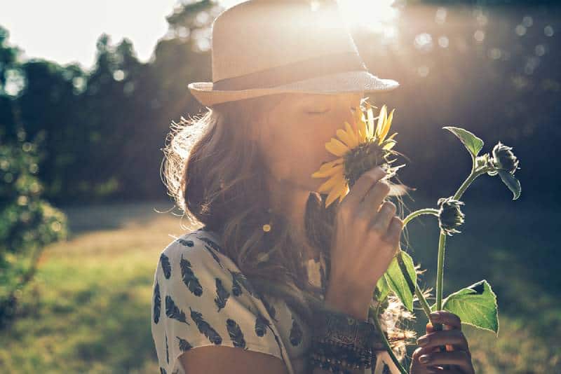 girl smelling sunflower in nature