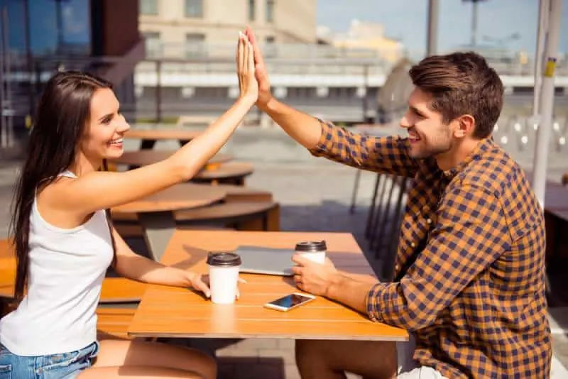 happy couple doing high five at cafe