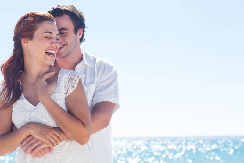 happy couple hugging and smilling at beach