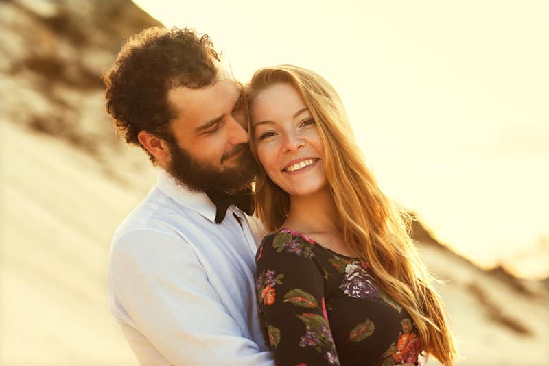 casal feliz abraçado na praia