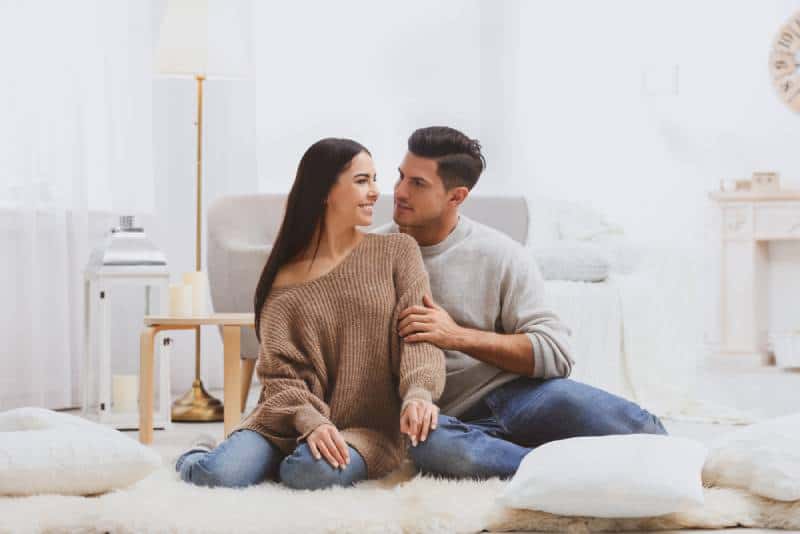 happy couple sitting on bed in bedroom