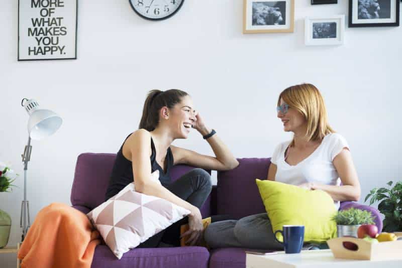 happy female friends talking in living room