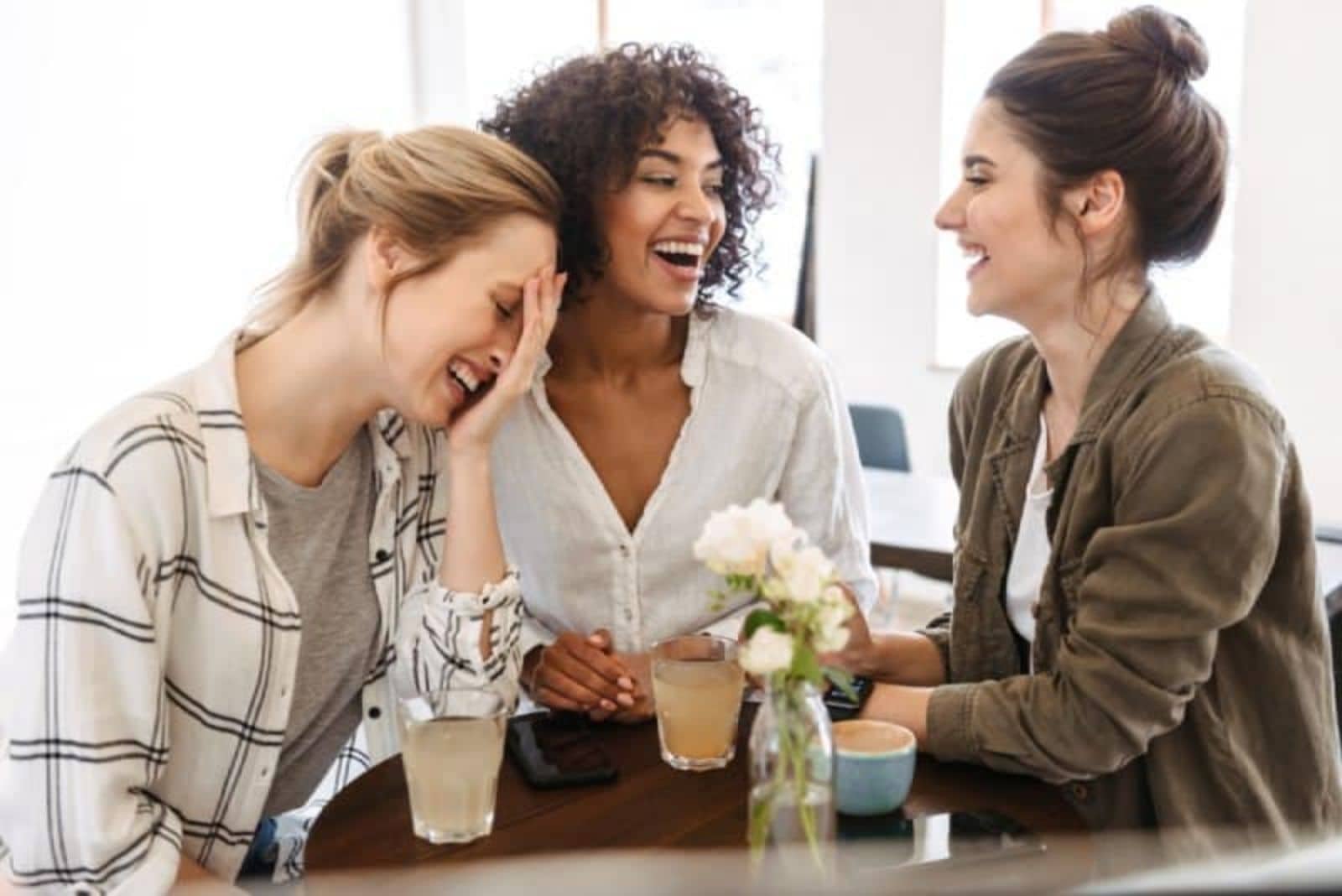 mulher feliz com amigos a ter uma conversa positiva no café