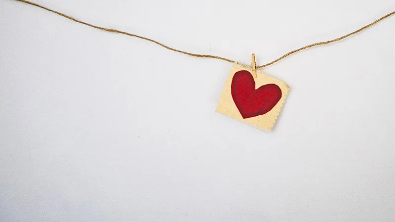 heart-shaped red and beige pendant hanging on string