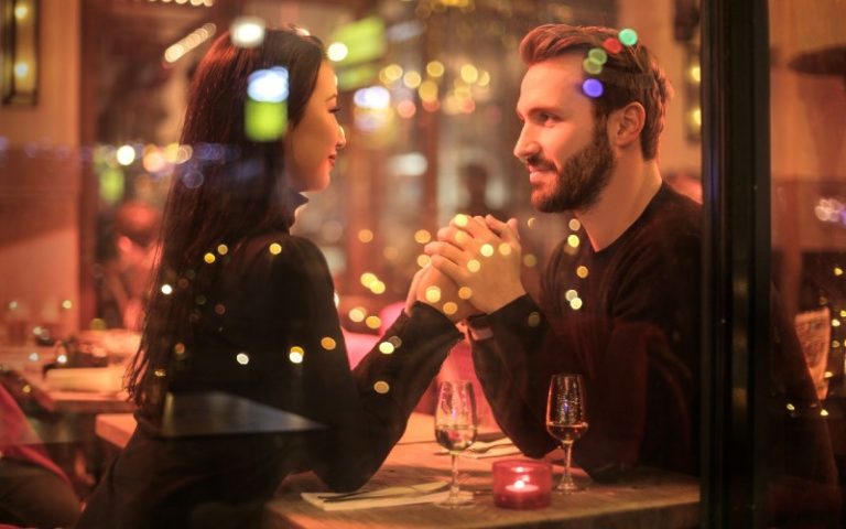 Happy couple sittitng on a table and holding hands
