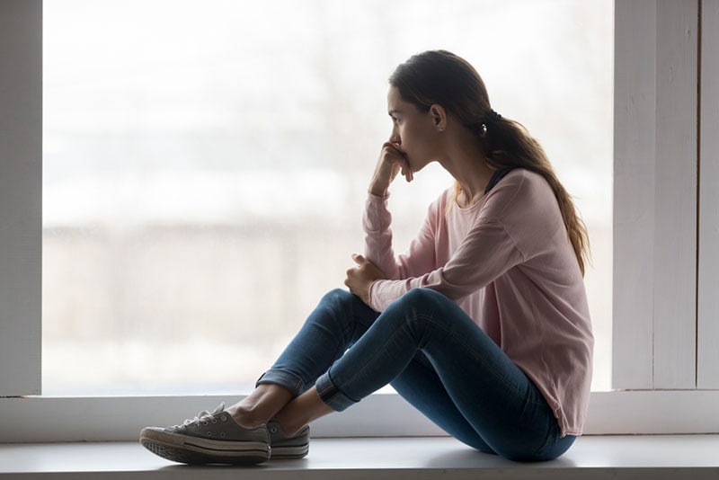 mujer solitaria sentada cerca de la ventana