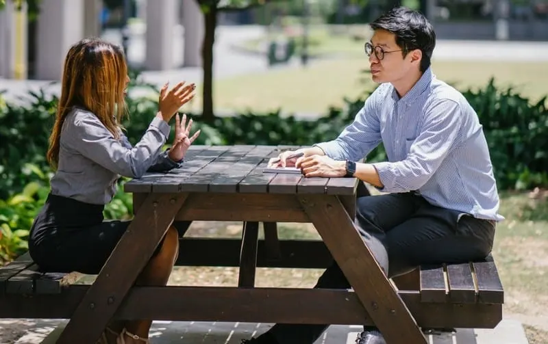male and female talking outside on table