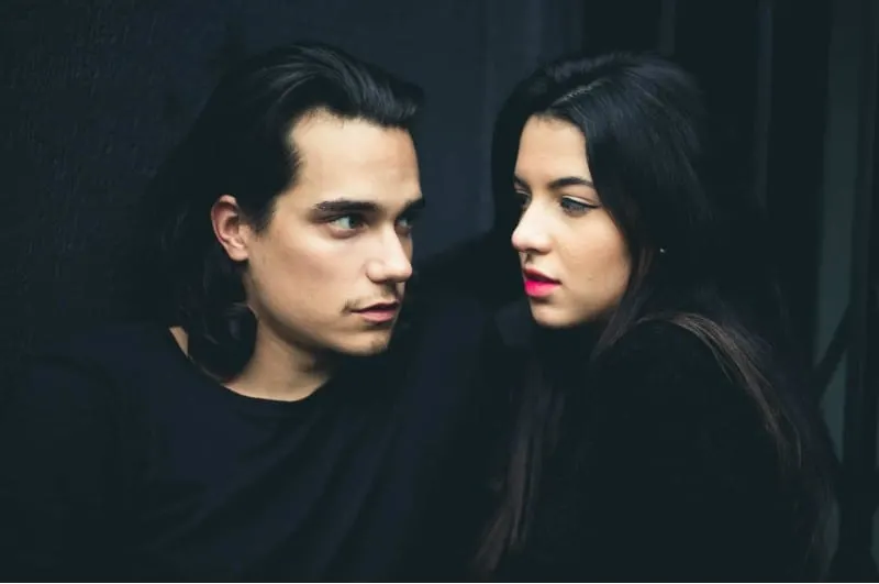 Young and sensual man and woman with dark hair in dark background