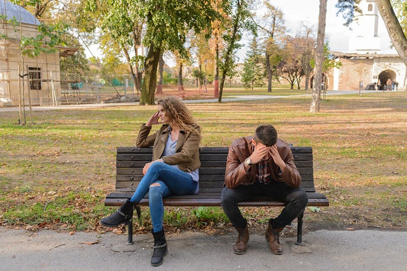 man and woman having conflict sitting on brown wooden bench