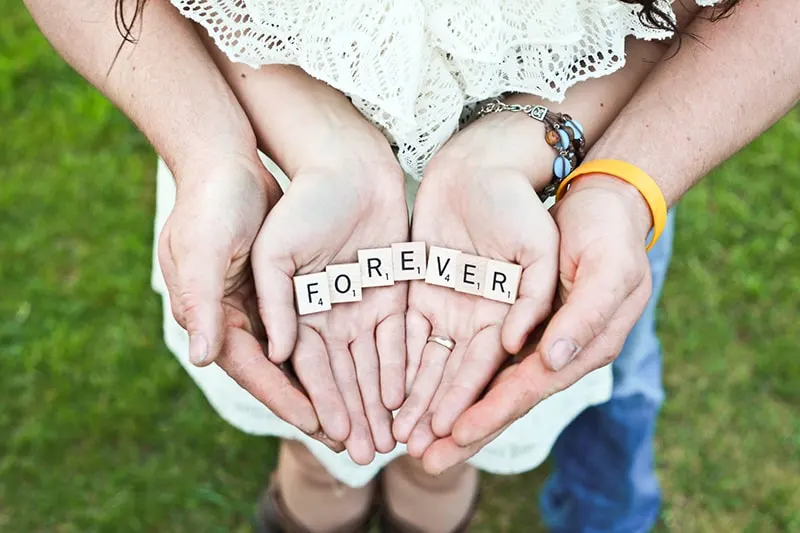 man and woman holding forever scrabble letters while standing on grass