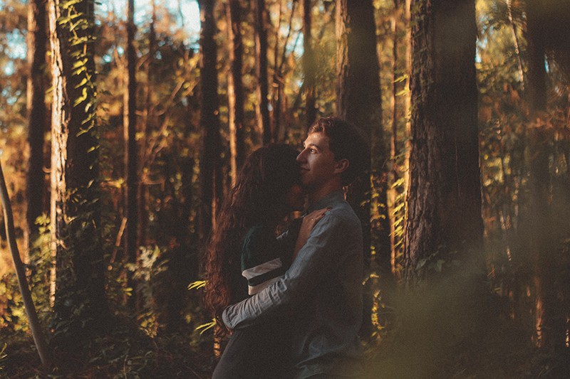 man and woman hugging each other in the forest